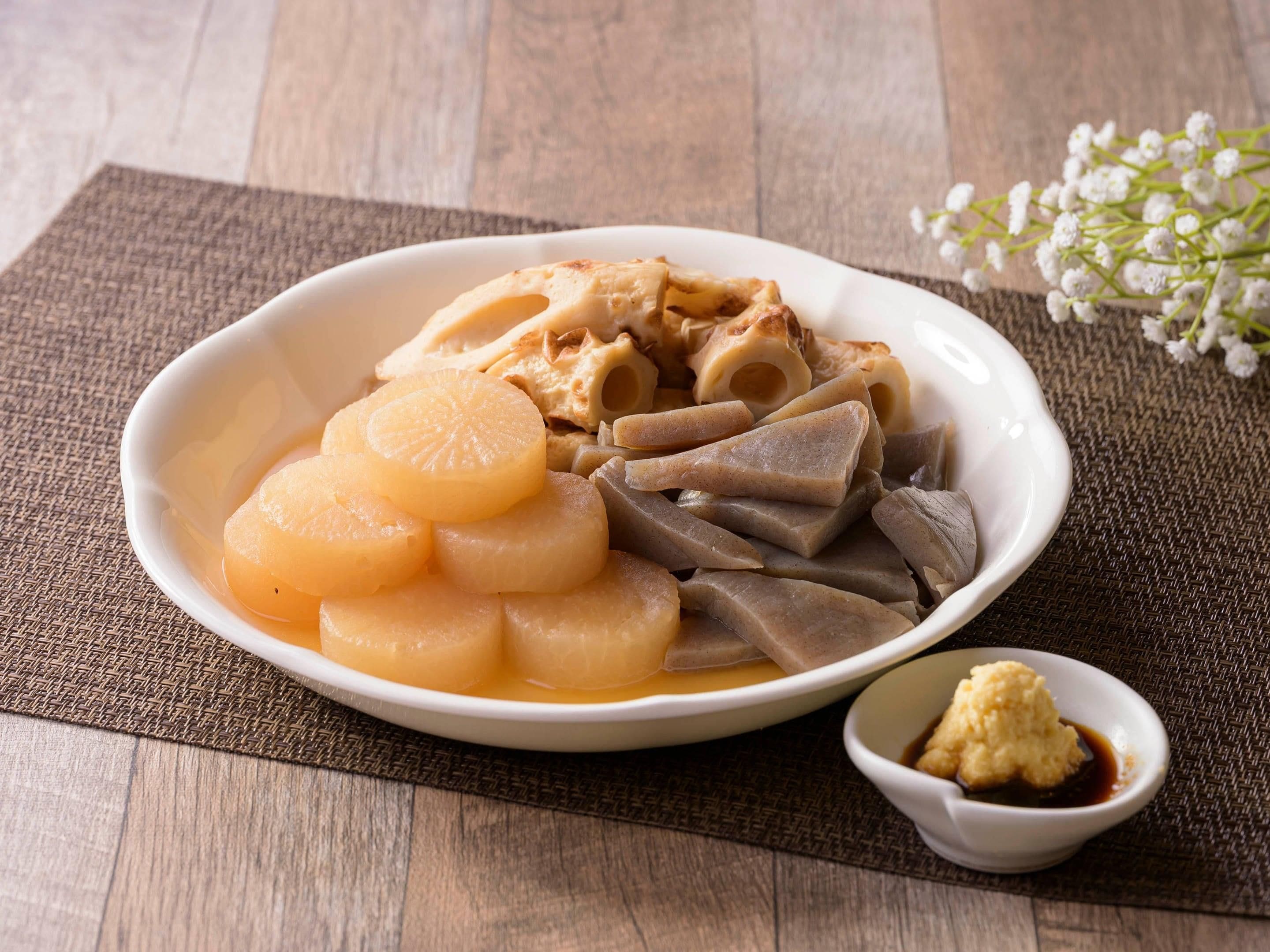 A bowl of food with various ingredients, a small bowl of sauce, and a decorative flower.