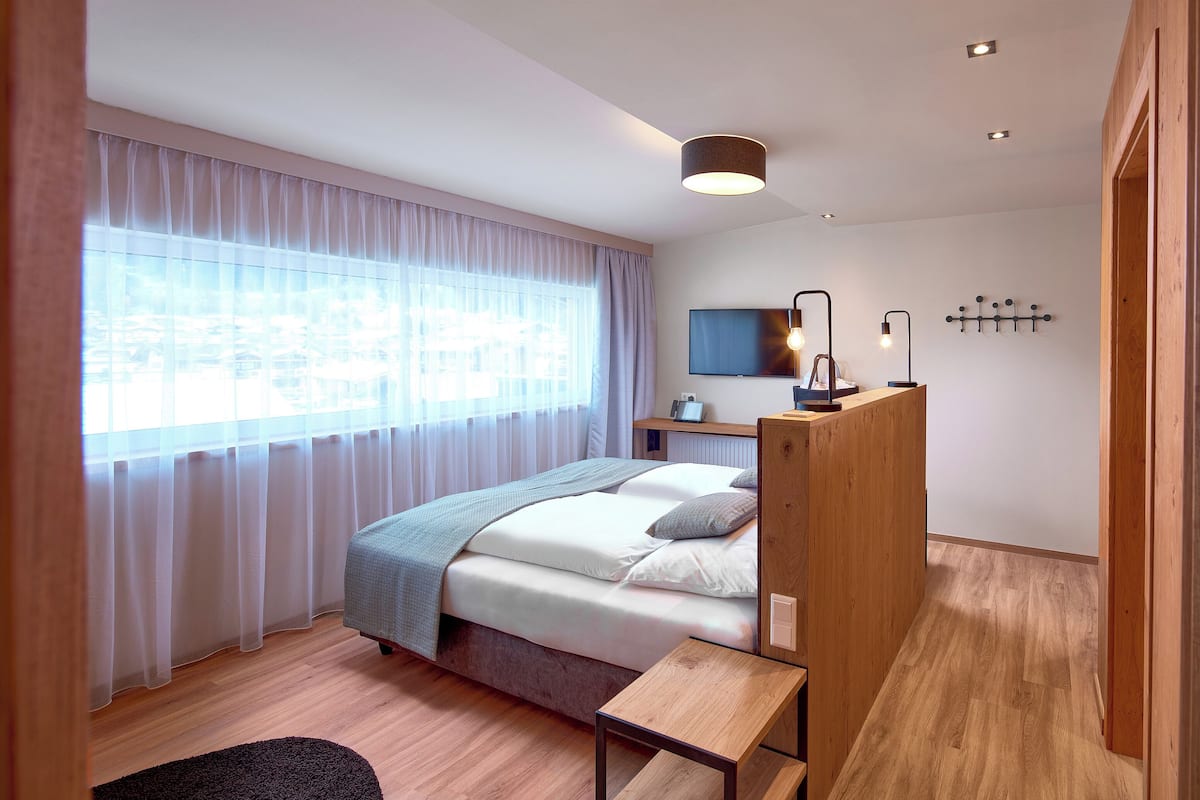A modern bedroom with a bed, bedside table, and a desk with a chair.