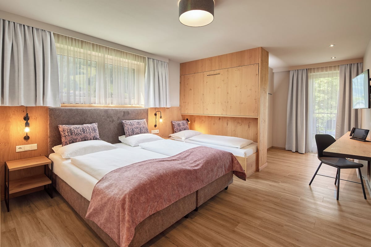A modern hotel room with two beds, a desk, and a chair.