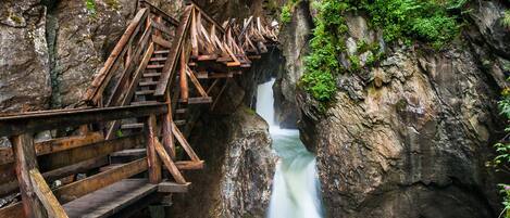 A wooden bridge over a fast-flowing river in a rocky gorge.