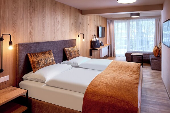 A hotel room with two beds, a TV, a desk, and a window with curtains. - Hotel Sonnblick (Kaprun)