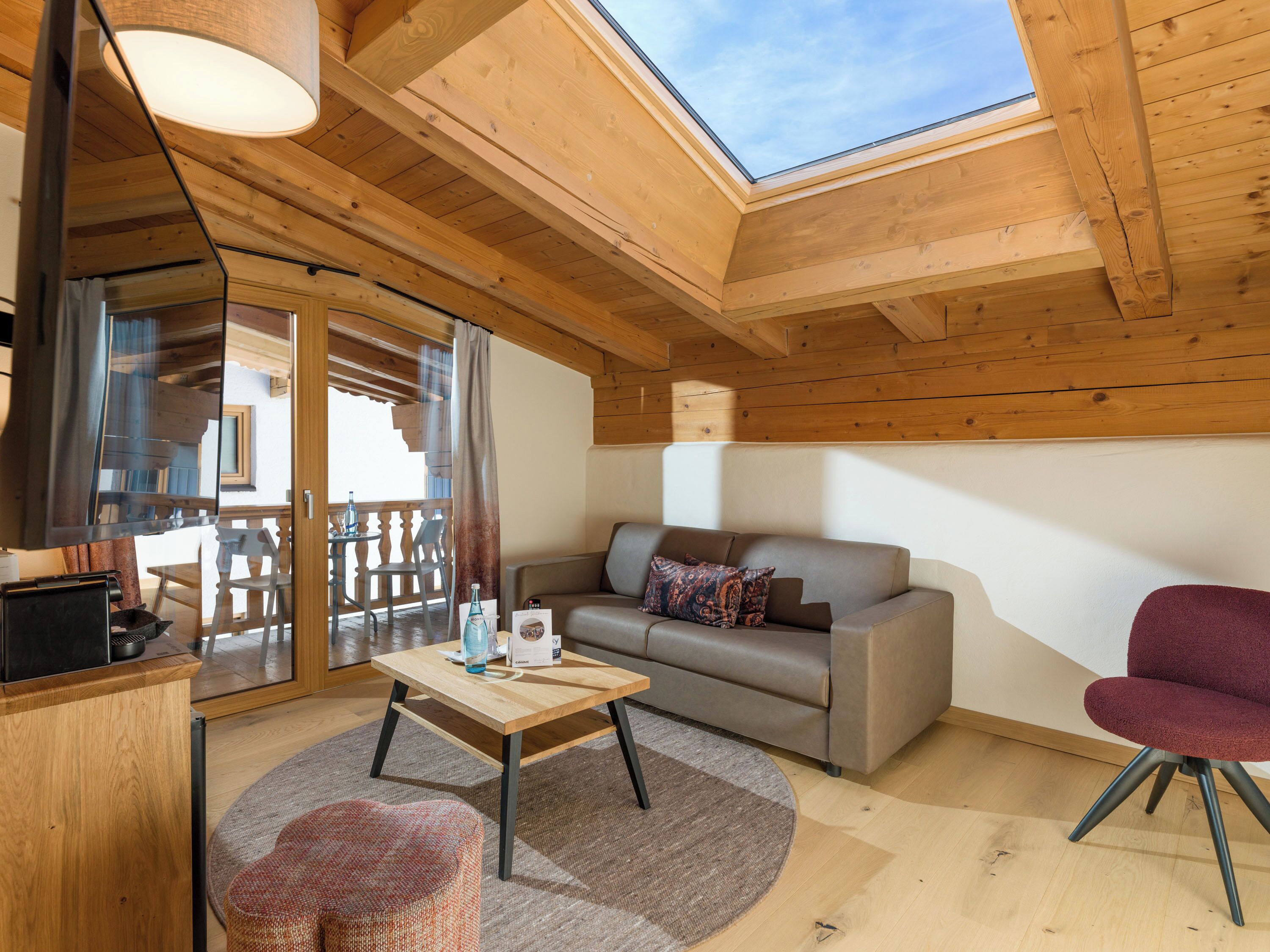 Una habitación acogedora con techo de madera, un sofá, una mesa y una silla.