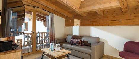 Una habitación acogedora con techo de madera, un sofá, una mesa y una silla.