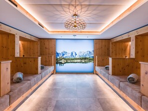 Un cuarto de spa con paredes de madera, un ventanal con vistas a la montaña y un área de estar central.