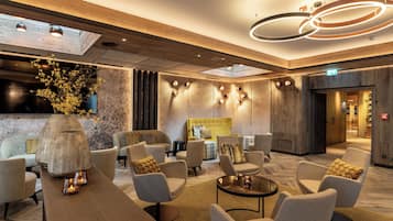 A modern lounge area with sofas, a coffee table, and a large vase with dried flowers.