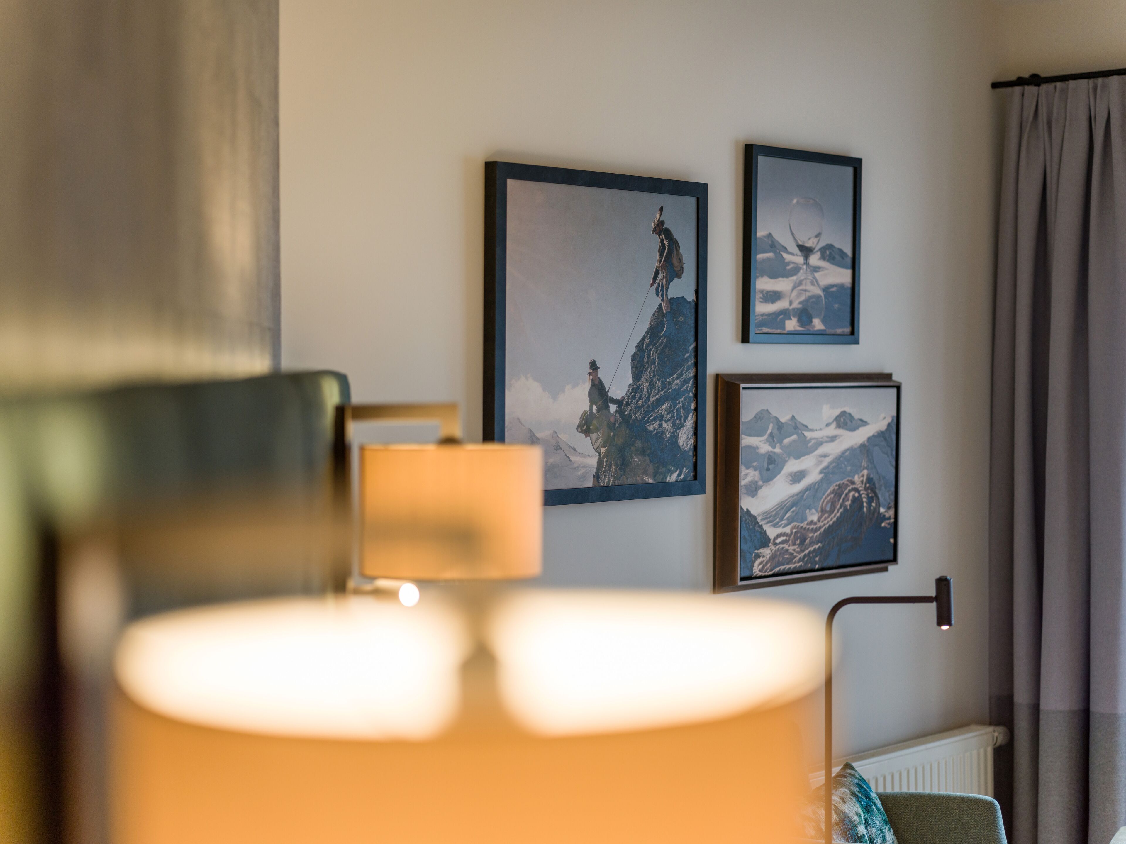 A room with a lamp, a radiator, and three framed pictures on the wall.