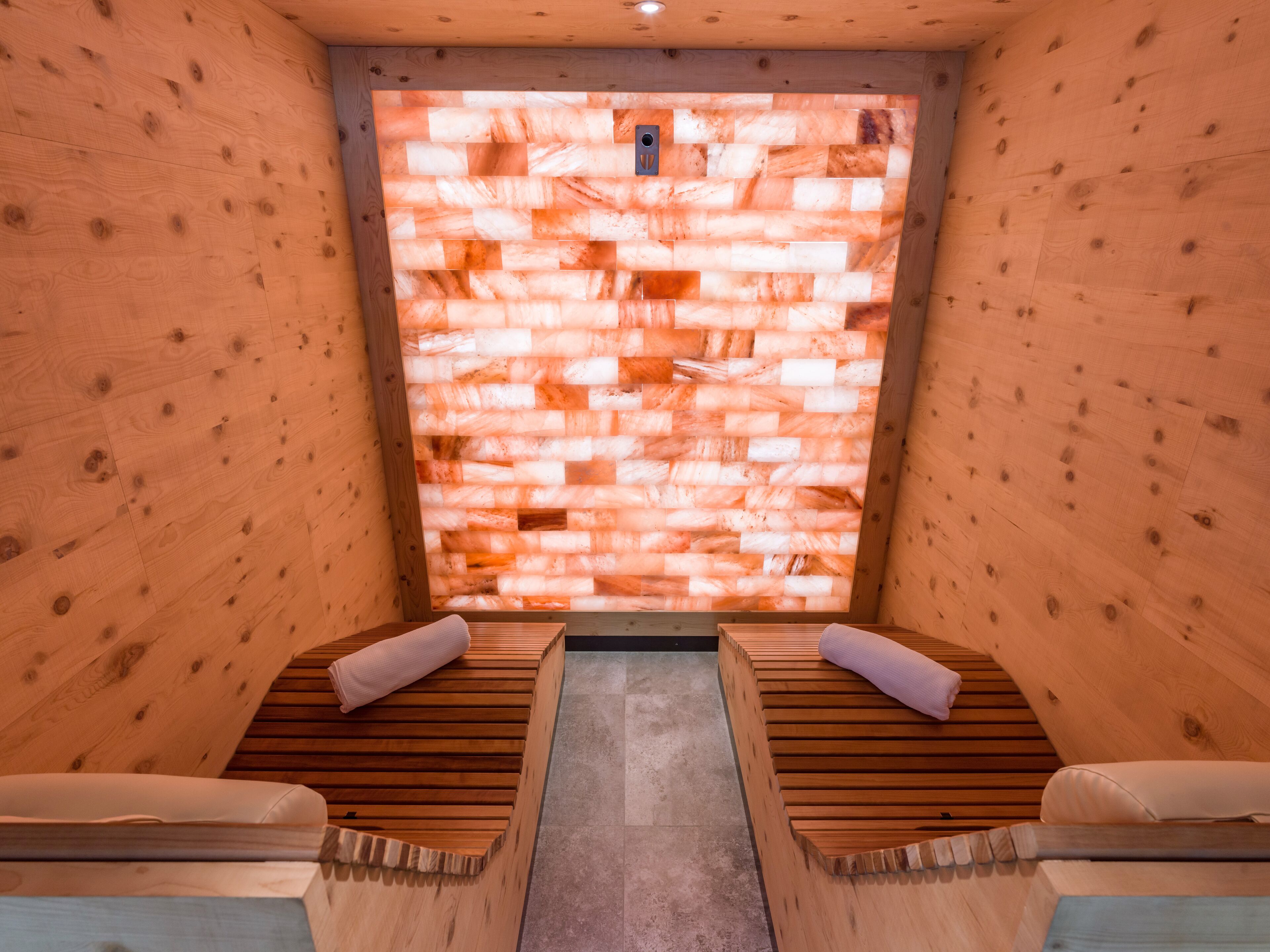 Una sala de sauna con bancos de madera y una pared de sal.