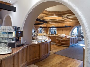 A spacious cafe with wooden interiors, a coffee machine, and a variety of seating areas.