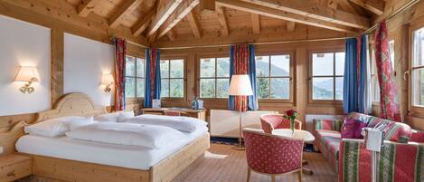 A wooden cabin room with a bed, a desk, a chair, and a sofa.