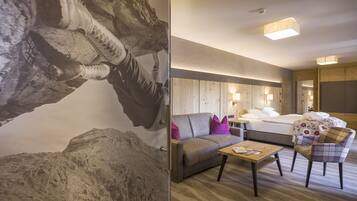 A hotel room with a bed, a sofa, a chair, a table, and a wall with a textured mural.