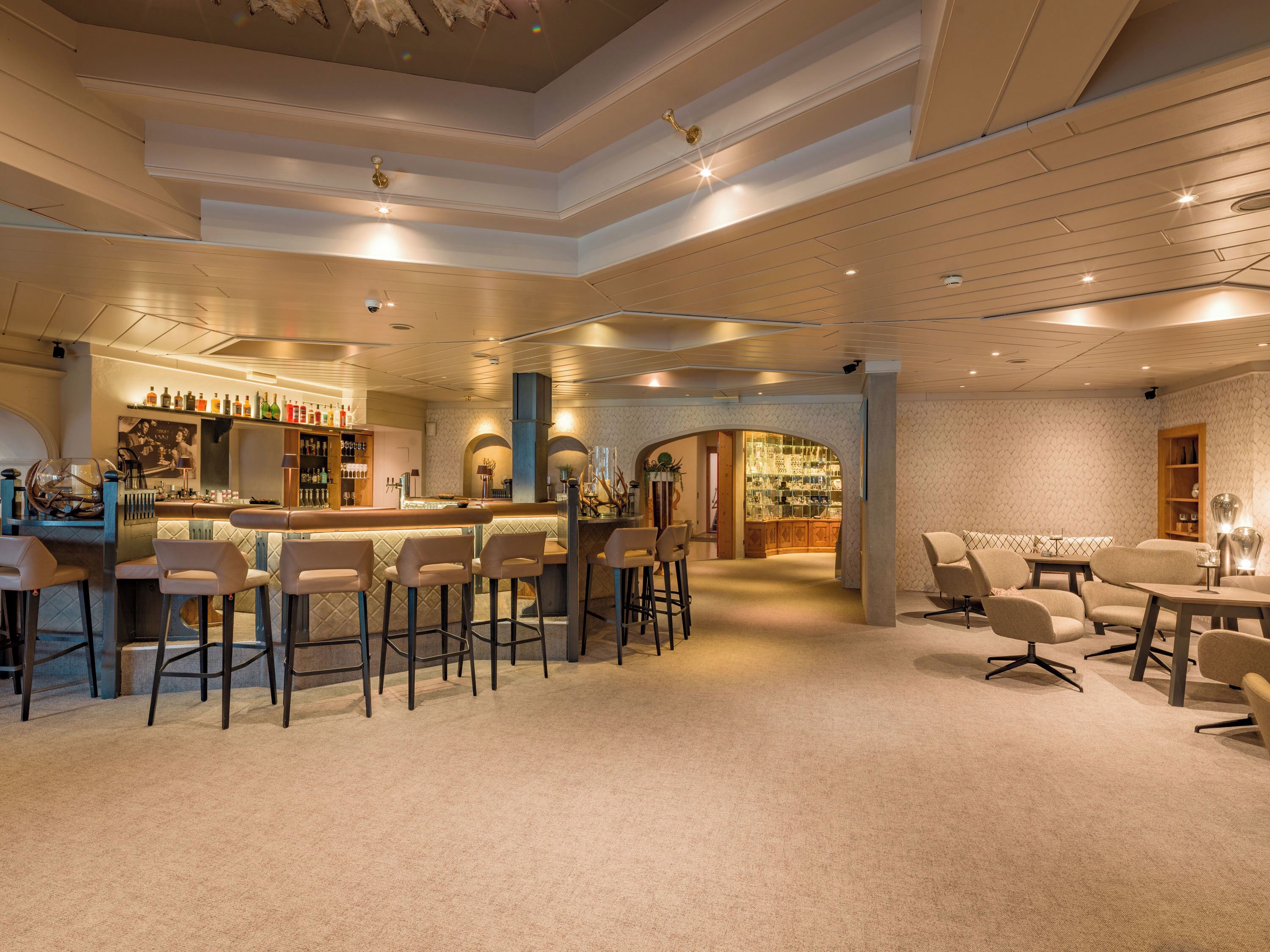 A spacious bar area with high stools, a bar counter, and a seating area with tables and chairs.