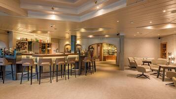 A spacious bar area with high stools, a bar counter, and a seating area with tables and chairs.