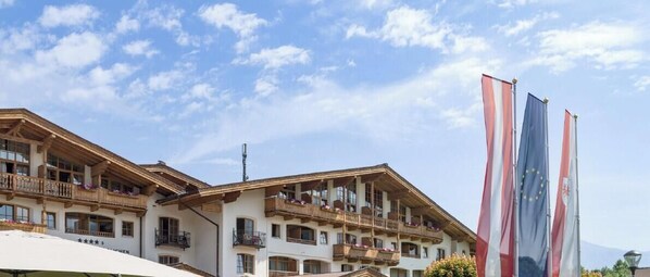 A multi-story hotel with balconies, European Union flags, and a clear sky.