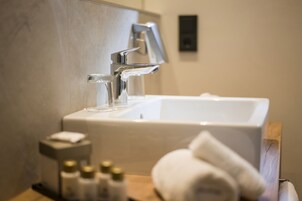Un baño con lavamanos blanco, espejo y toalla.