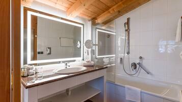 A modern bathroom with a wooden ceiling, a large mirror, a sink, and a bathtub.