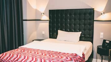 Ein Hotelzimmer mit einem großen Bett, einem dunklen Kopfteil und zwei Wandleuchten.
