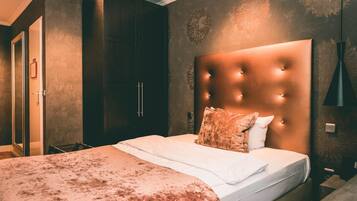 A bedroom with a large bed, dark wooden wardrobe, and a decorative wall.