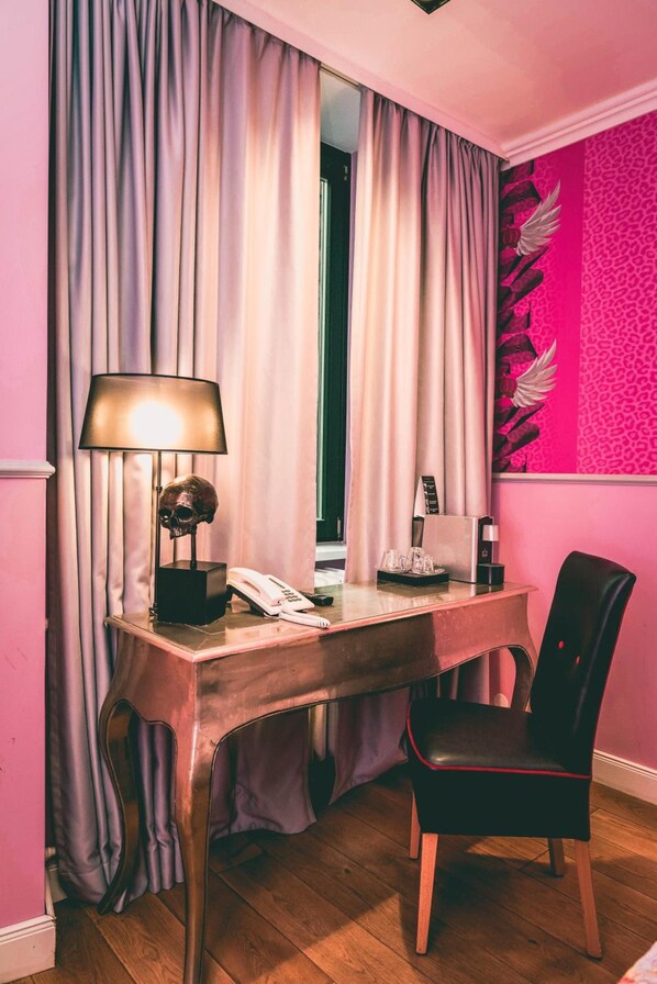 A room with a desk, chair, lamp, and a telephone.