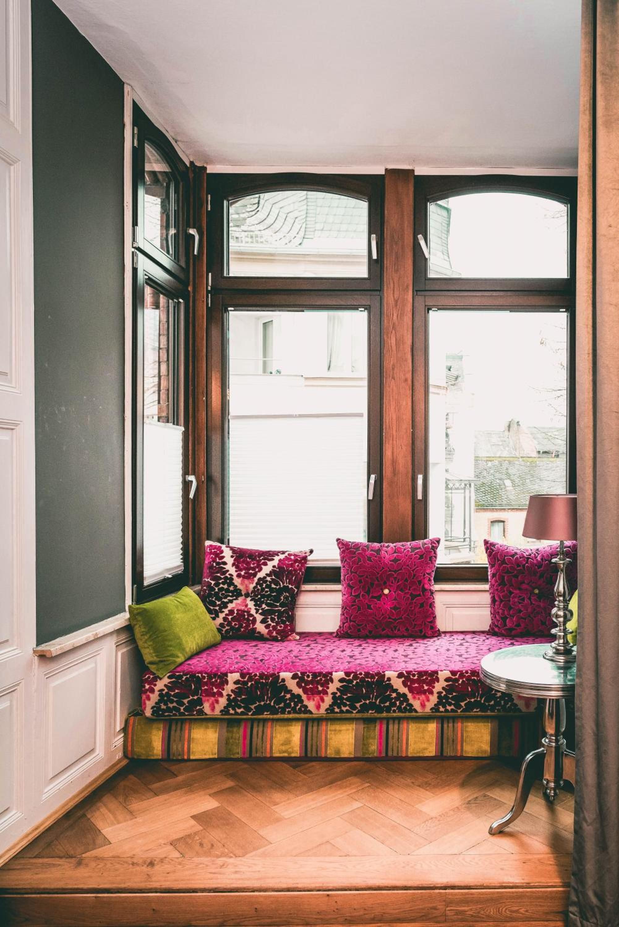 Un coin salon avec un banc, des coussins et une lampe.
