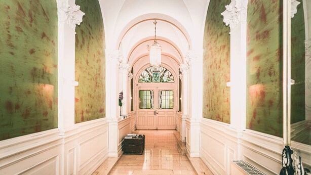A hallway with a green wall, white trim, a large arched doorway, and a radiator. - Hotel Villa Klemm - Wiesbaden City (Wiesbaden)