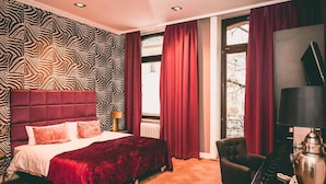 A room with a zebra-patterned wall, a red upholstered headboard, a bed with white and pink bedding, a red curtain, a piano, and a lamp. - Hotel Villa Klemm - Wiesbaden City (Wiesbaden)
