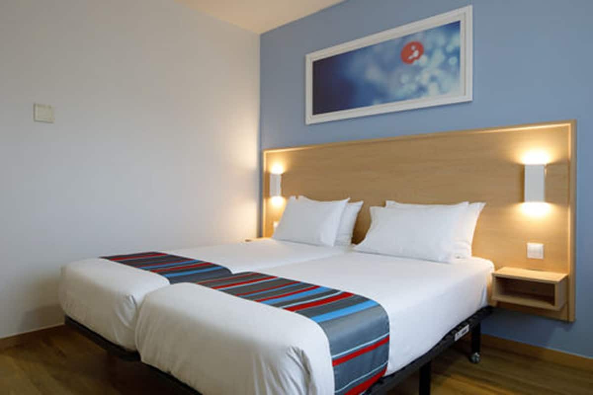 Una cama doble con una colcha a rayas, dos mesitas de noche con lámparas y un cuadro enmarcado en la pared.
