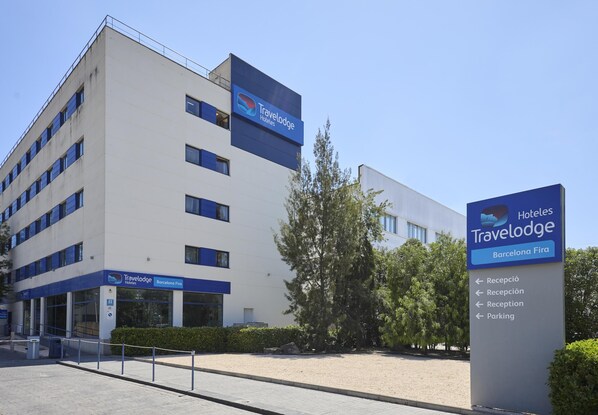 Un bâtiment d’hôtel Travelodge avec une enseigne indiquant la réception et le parking.