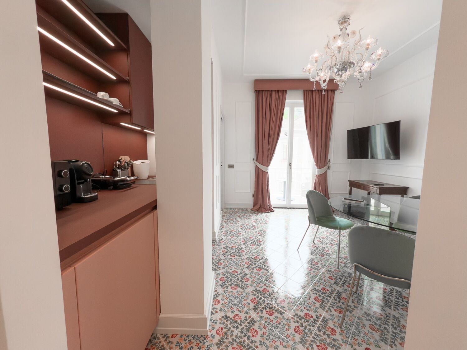 Una cocina moderna con electrodomésticos integrados, una zona de comedor con mesa de vidrio y un televisor montado en la pared.