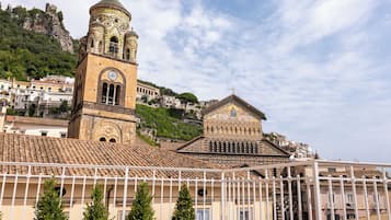Un edificio histórico con una torre de campanas y una estructura más pequeña, rodeado de viviendas y una colina.