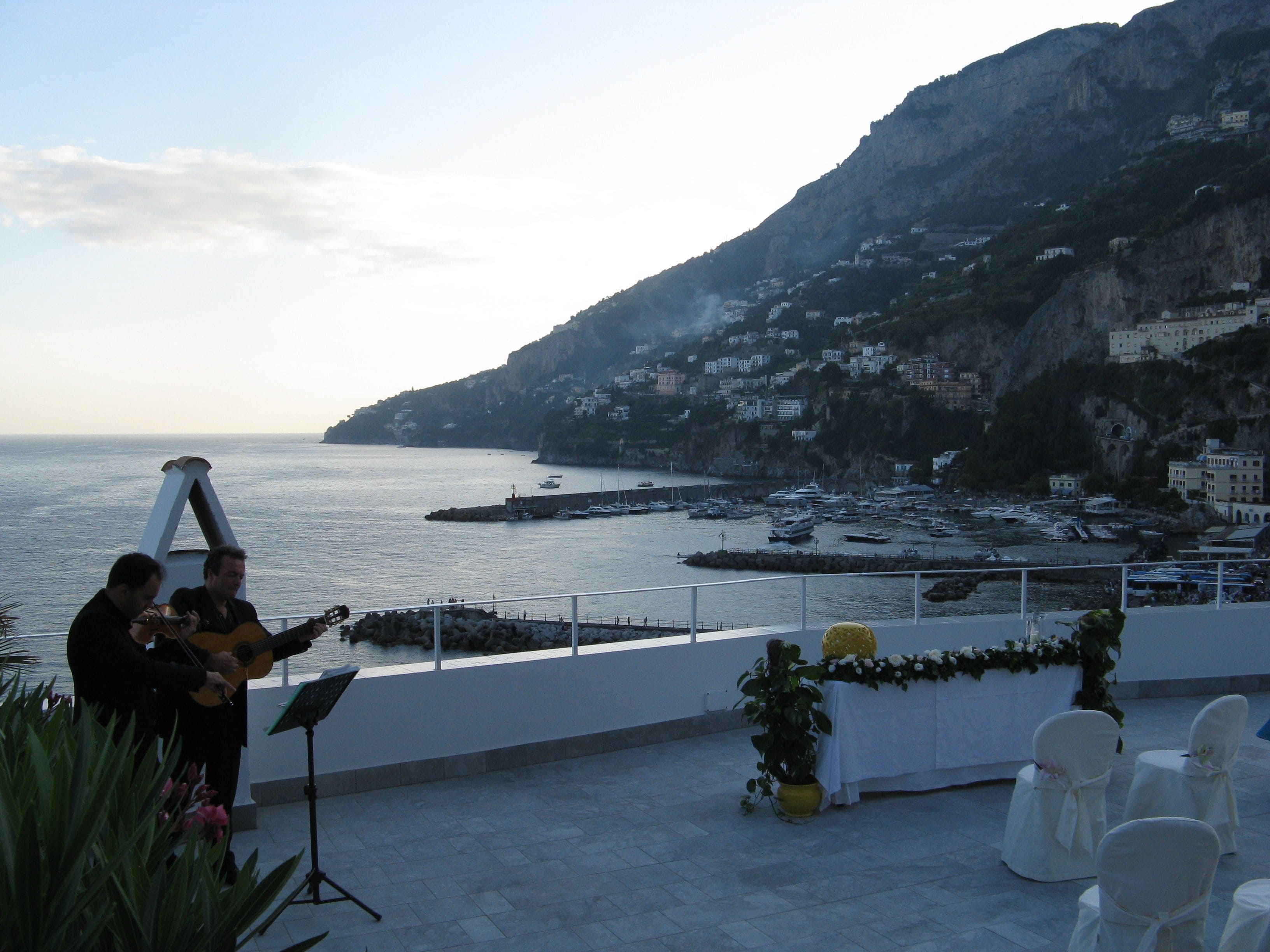 Une terrasse en bord de mer offrant une vue sur l’océan et dominée par un paysage montagneux.