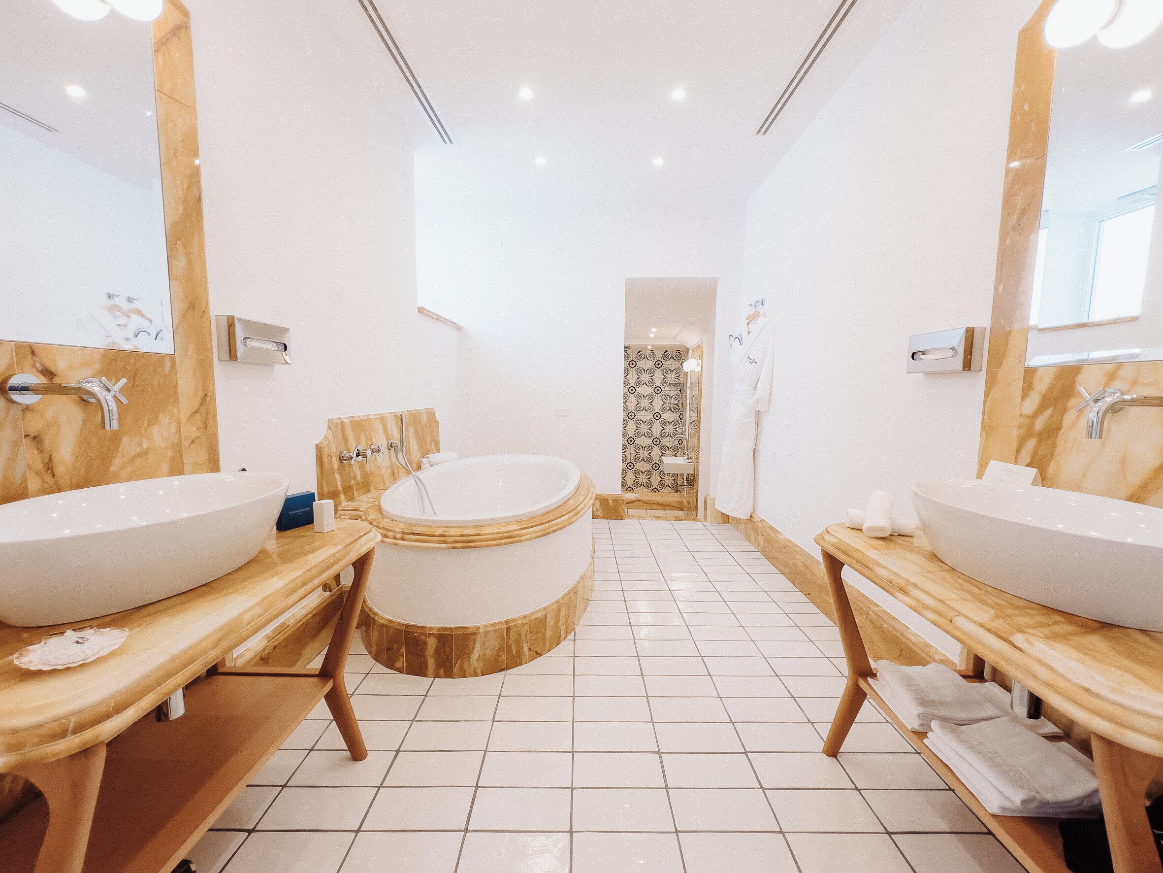 A modern bathroom with two large sinks, a freestanding bathtub, and a mirror above each sink.