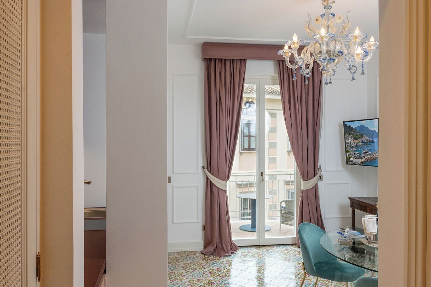 Una habitación con una mesa de cristal, un candelabro y vistas al mar.