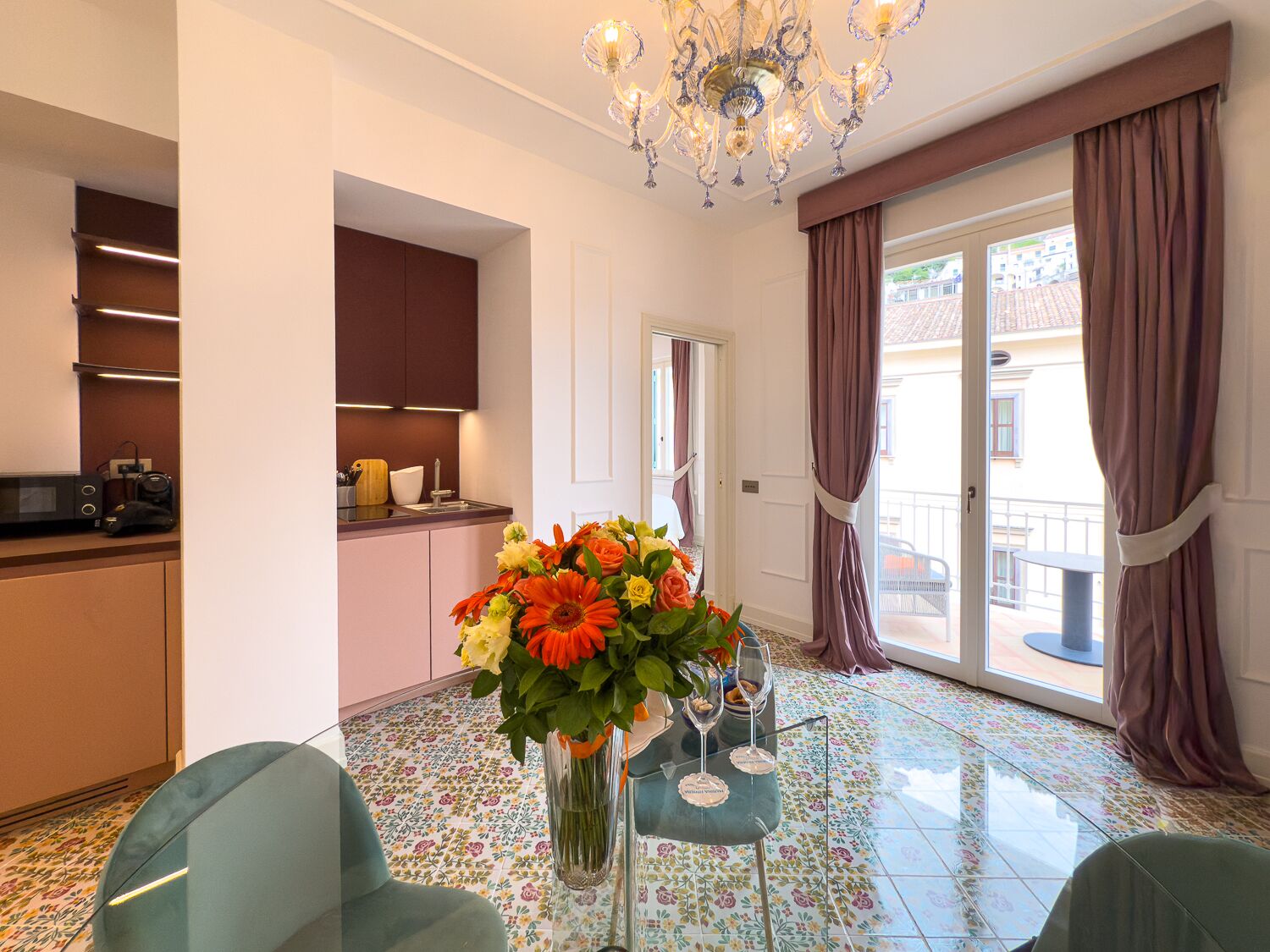 A modern kitchen with a dining area, a chandelier, and a view of the outside.