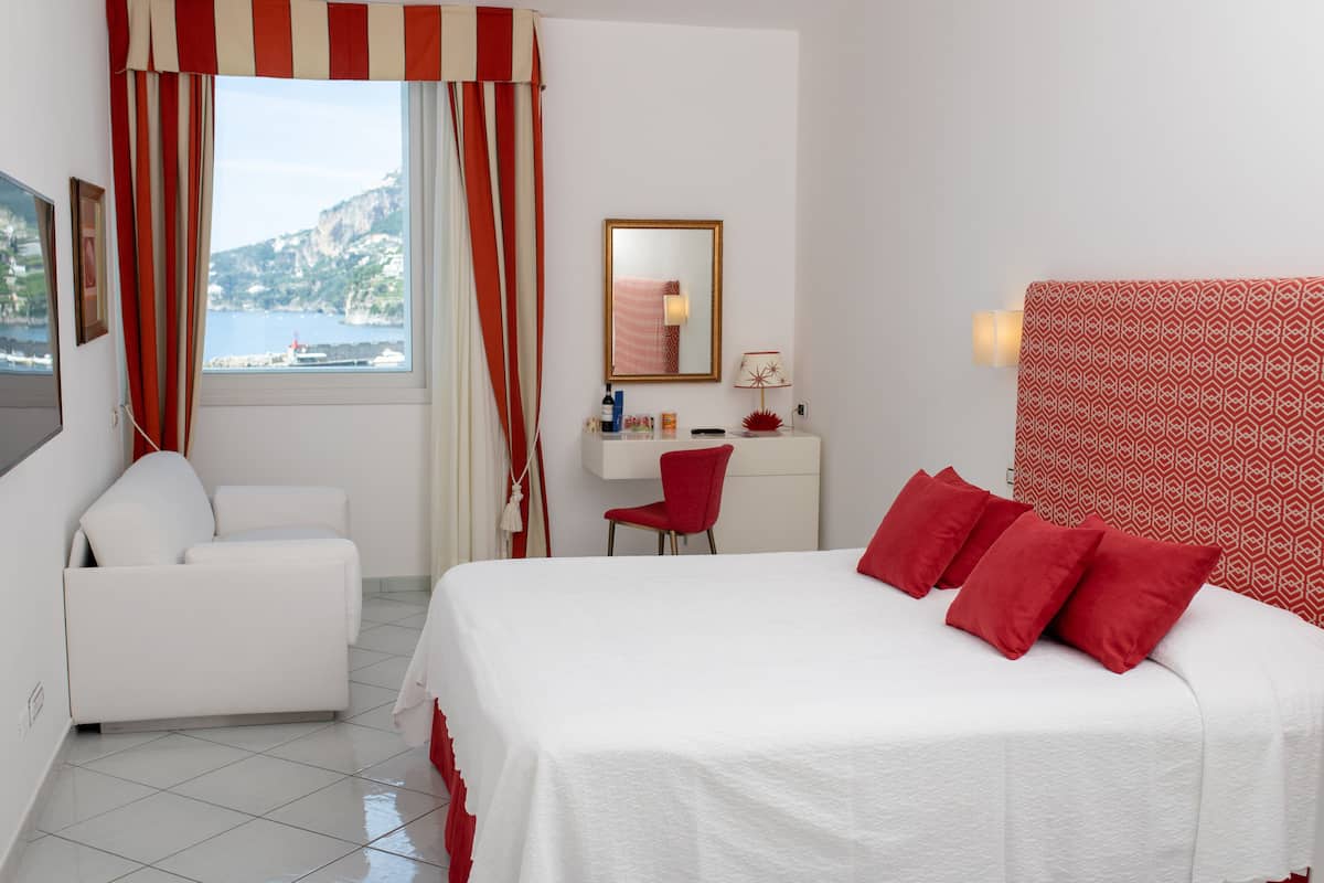 Ein Hotelzimmer mit Bett, Schreibtisch, Stuhl und Meerblick.