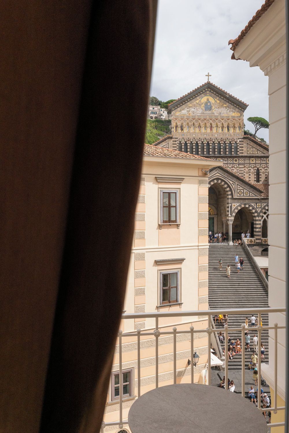Vista de un edificio con una cruz en la parte superior, una escalera y personas en los escalones.