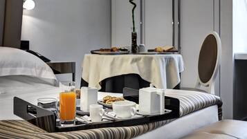 Una camera d'albergo con un vassoio per la colazione ordinato sul letto, un comodino con un vaso e uno specchio.