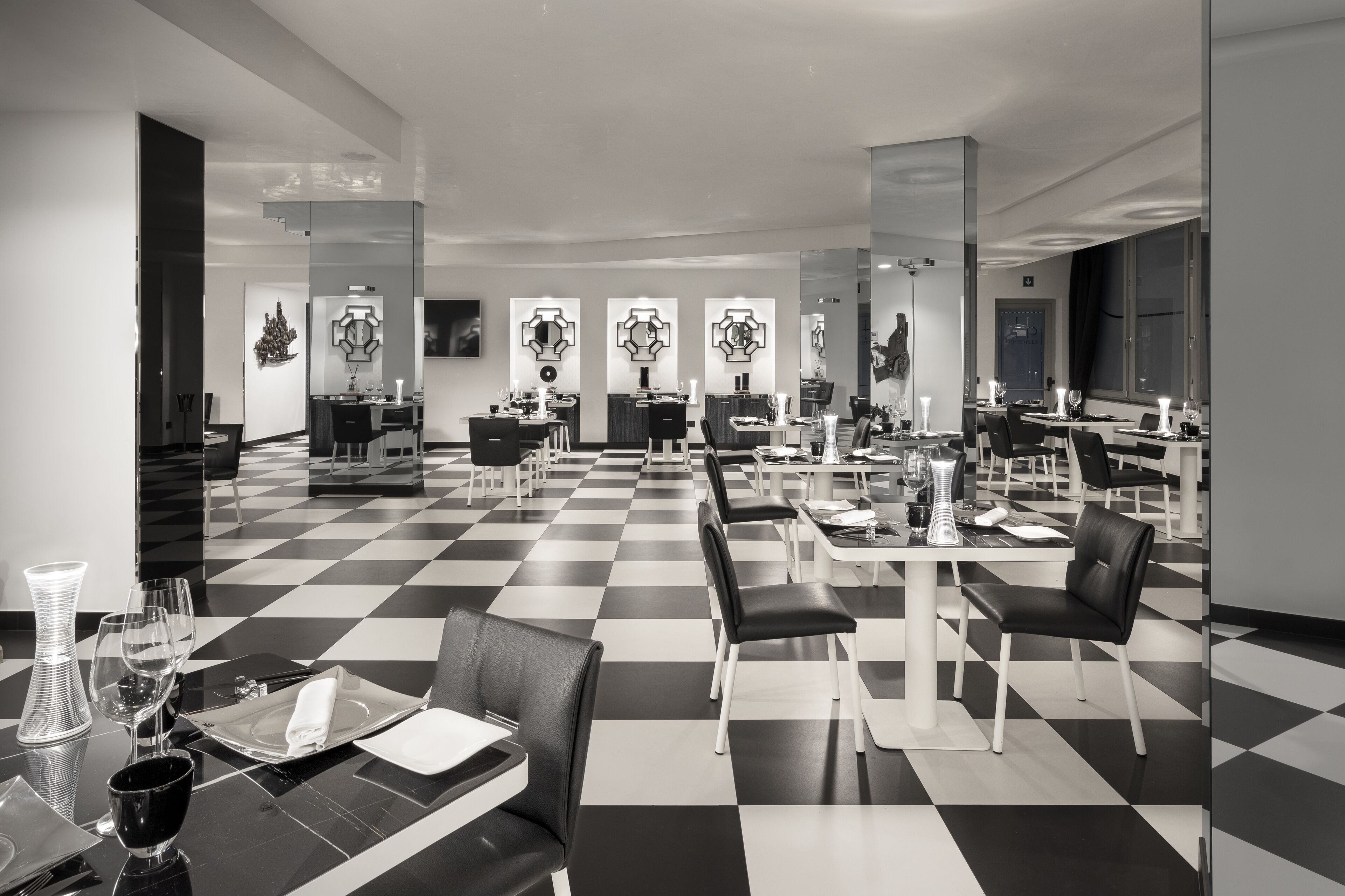 A modern hotel lobby with checkered flooring, black and white furniture, and contemporary decor.