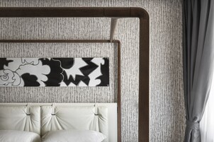 Una camera da letto con una parete strutturata, una testiera e un letto con testiera bianca.