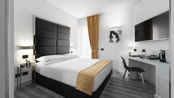 Een moderne hotelkamer met een groot bed, een bureau met stoel, een flatscreen televisie en een kleine kitchenette.
