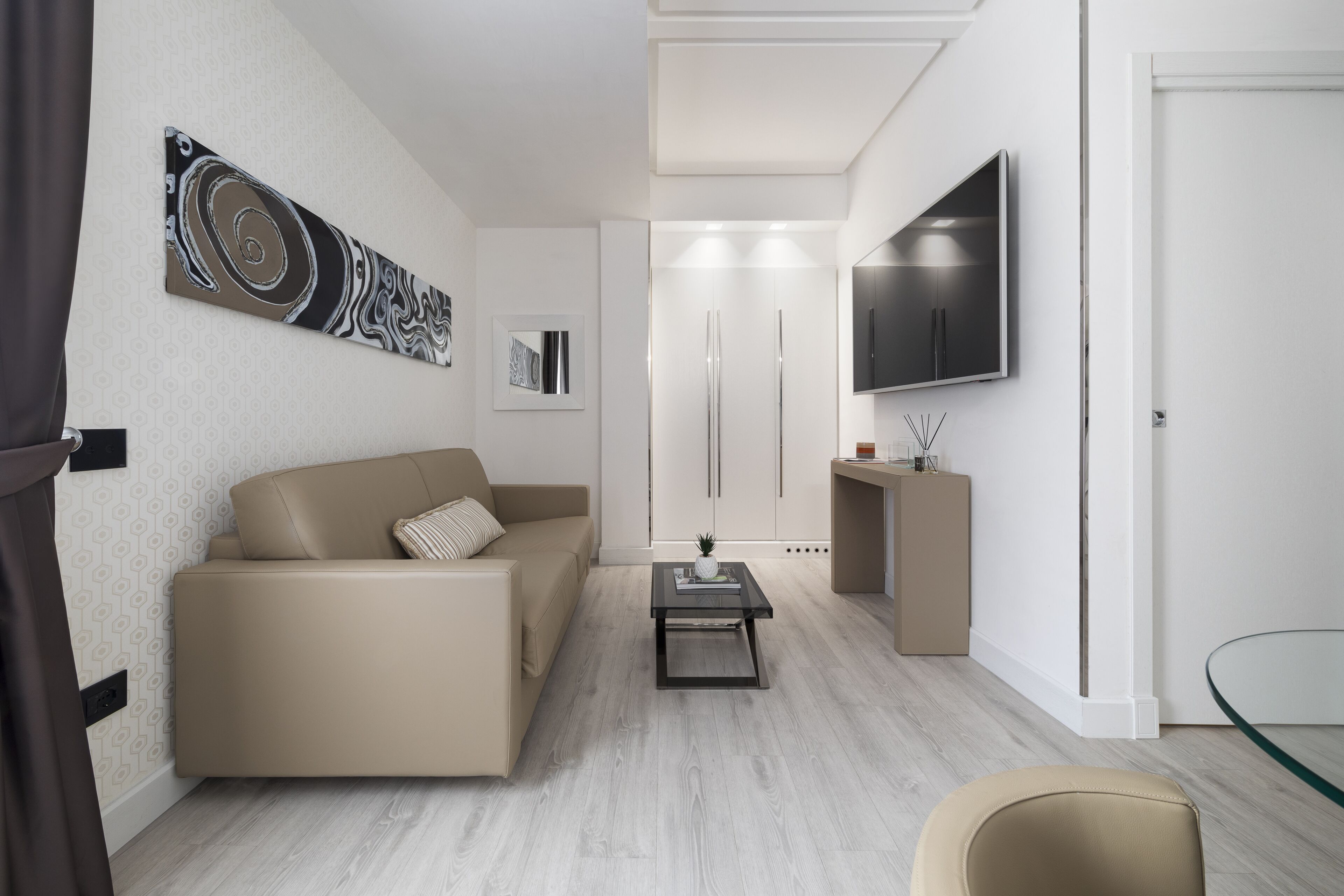 A modern living room with a sofa, a coffee table, and a TV mounted on the wall.