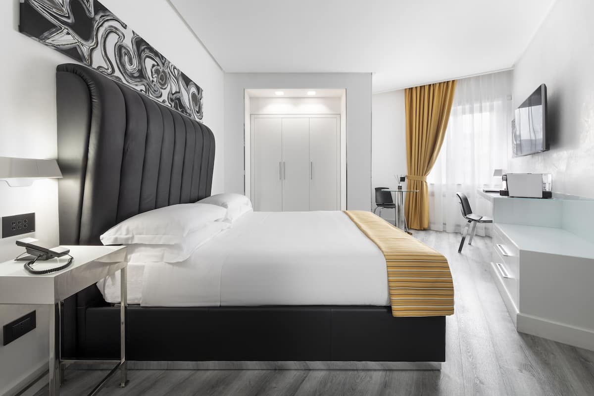 Une chambre d’hôtel moderne équipée d’un grand lit, d’un bureau avec une chaise, d’une télévision et d’une armoire.