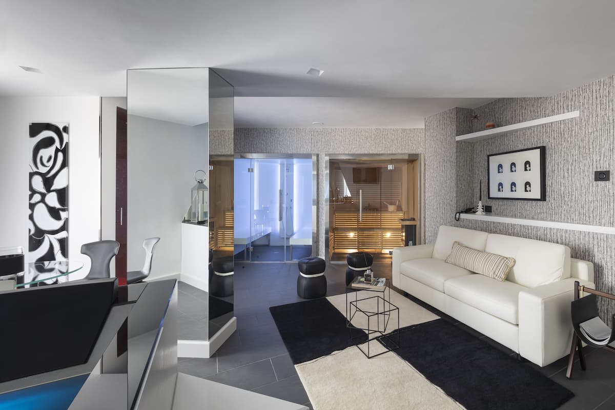 Un salon moderne avec un canapé blanc, un tapis noir et blanc et une cloison en verre.