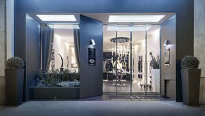 Una entrada de hotel moderna con puerta de cristal, mostrador de recepción y un candelabro.