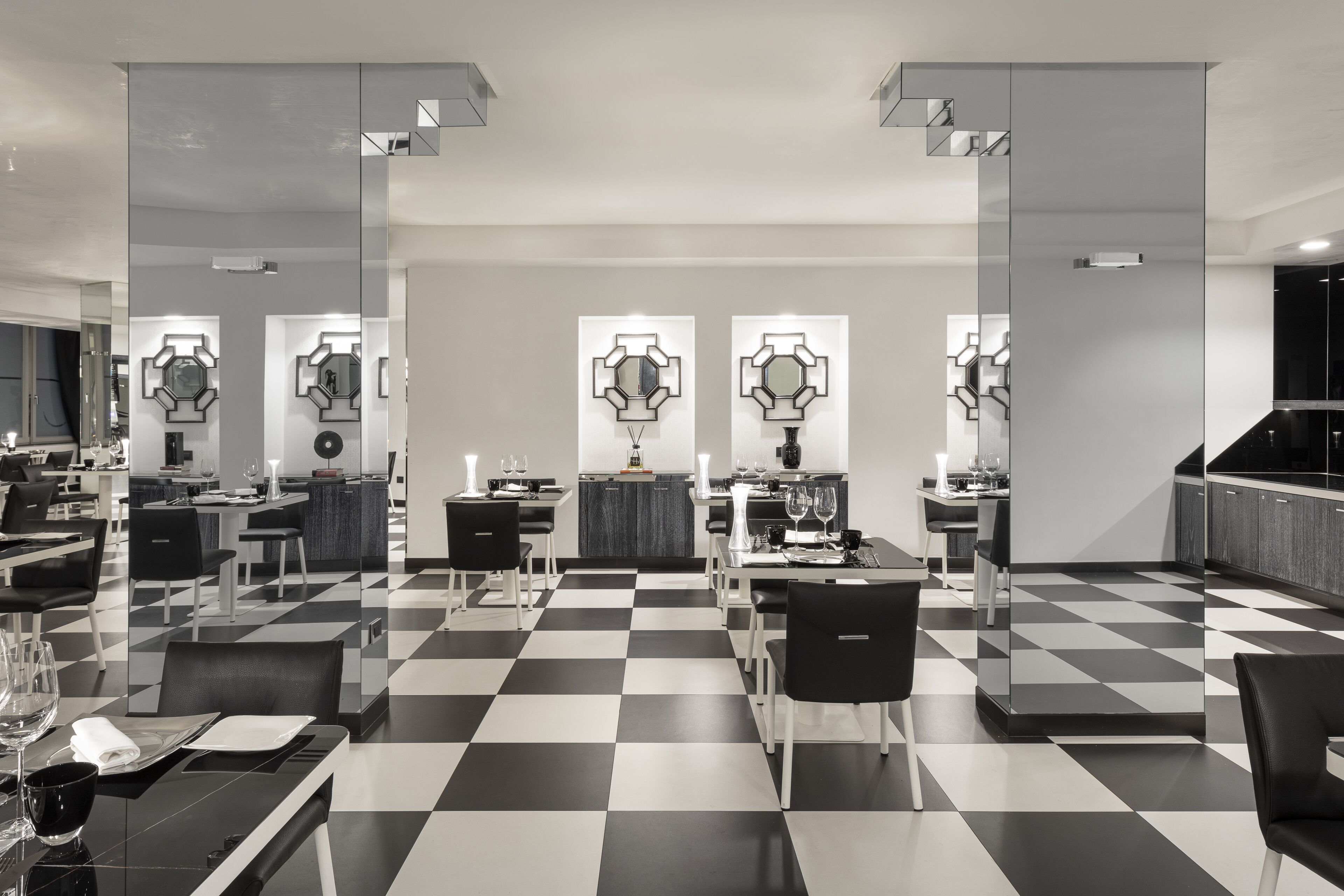 A modern dining area with checkered flooring, black and white chairs, and contemporary wall art.