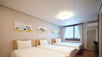 A hotel room with two beds, a window with curtains, and artwork on the wall.