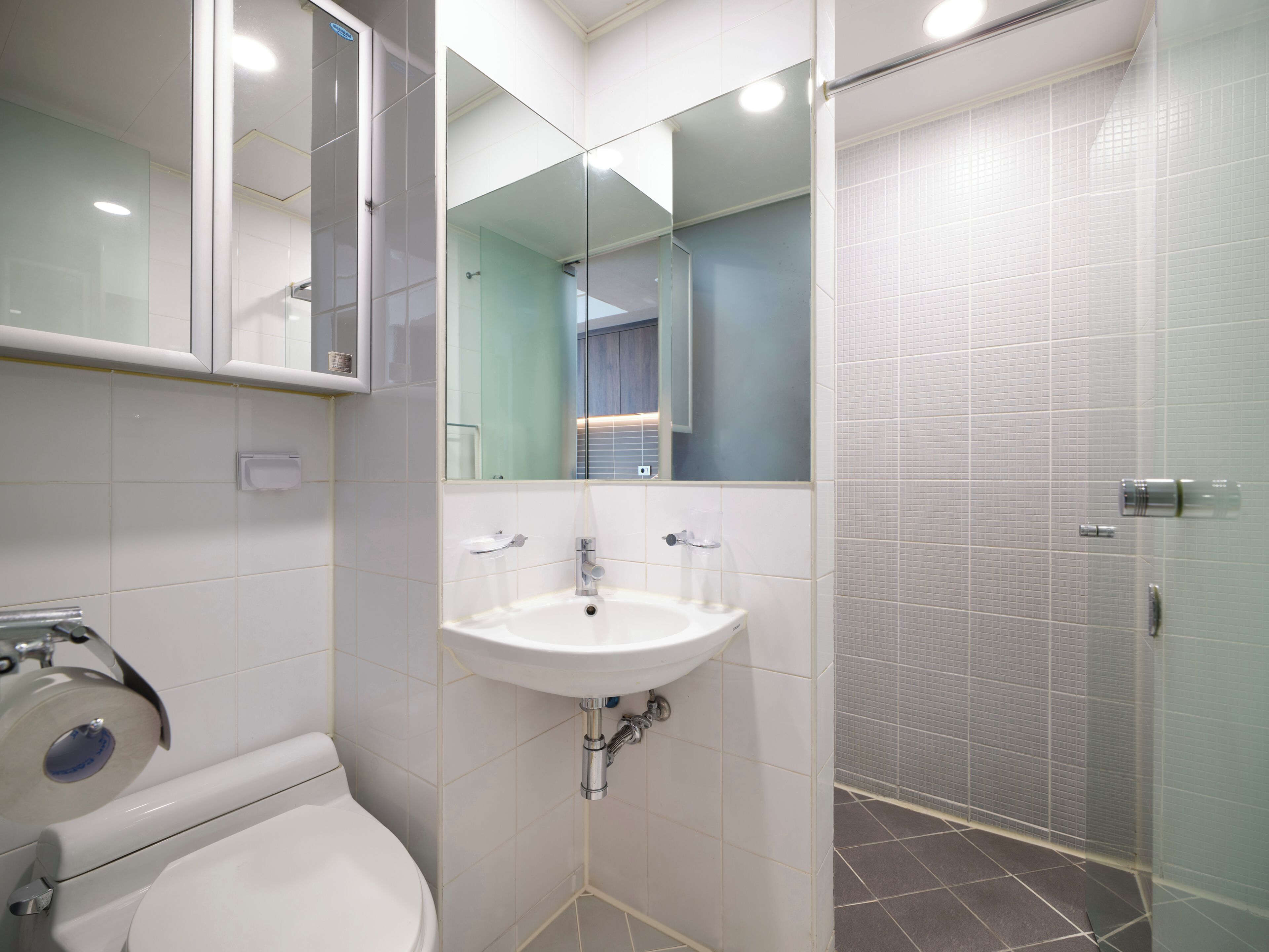 Un bagno con un lavandino bianco, un WC e un box doccia in vetro.