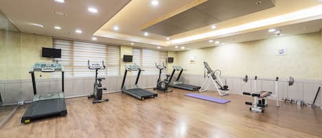 Un gimnasio con cintas de correr, elípticas y un banco para pesas.