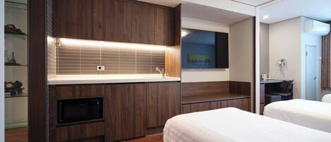 Una habitación de hotel moderna con un tocador de madera, una televisión de pantalla plana, una cama y un escritorio.