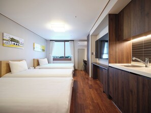 A hotel room with two beds, a large window, a modern kitchen with a sink, and artwork on the walls. - Western Coop Residence Dongdaemun (Seoul)