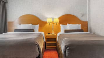 A hotel room with two beds, a nightstand with lamps, and a carpeted floor.
